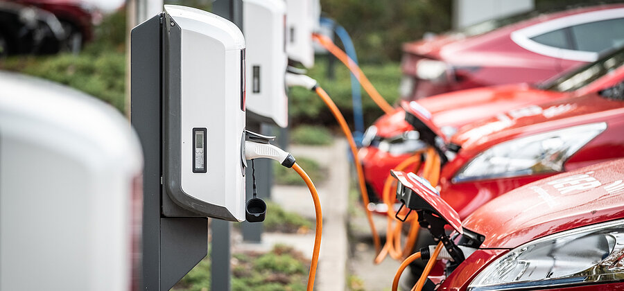 Eine Reihe roter Autos an Ladessäulen
