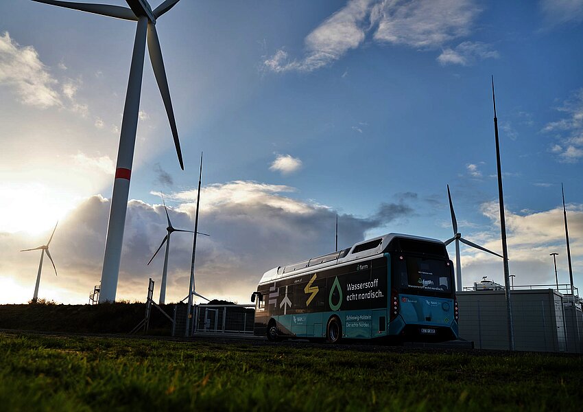 Ein Wasserstoffbus vor Windrädern